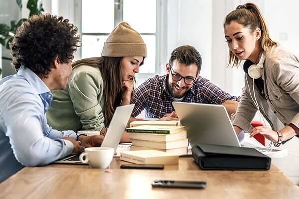Four people sitting around a computer on a desk